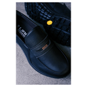 Black slip-on shoes with brand logo on a textured surface