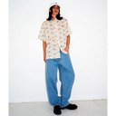Person wearing a floral shirt and blue jeans against a white background