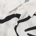Close-up of a white shirt with black abstract patterns and buttons.