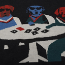 A close-up of a knitted sweater featuring stylized dog characters seated around a white table with playing cards on a black background.