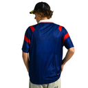 Person wearing a blue sports jersey with red accents on a white background