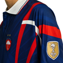Blue sports jersey with red and white stripes featuring Helas logos on a white background