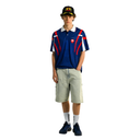 Person wearing a blue polo shirt with red and white accents, beige shorts, and a black cap on a white background