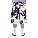 Person wearing black and white cow print shorts on a white background