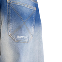 Close-up of the back pocket of light blue denim jeans with a white embroidered 'HOMEBODY' logo on the pocket, set against a plain white background.