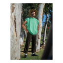 Man wearing a green t-shirt and straw hat standing in a park with trees.