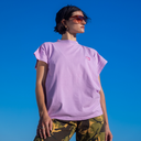 Person wearing a purple t-shirt and camouflage pants against a clear blue sky