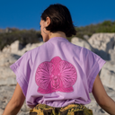 Person wearing a purple t-shirt with a pink orchid design on the back, standing outdoors.