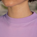 Close-up of a person wearing a light purple shirt with a blurred background
