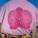 Person wearing a pink t-shirt with a large pink orchid design on the back, standing against a blue sky.