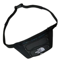 A black The North Face waist bag with a front zippered pocket, featuring the brand's logo and 'THE NORTH FACE' text in teal and white, shown on a plain white background.