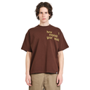 A young man wearing a brown oversized t-shirt with yellow text that reads 'here expand your mind' on the chest, paired with khaki pants, against a plain white background.