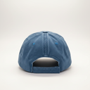A blue denim baseball cap viewed from the back, resting on a white surface against a neutral gray background.