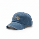 A washed blue denim baseball cap featuring a gold embroidered circular logo on the front, displayed on a clean white background.