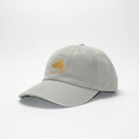 A light gray baseball cap with a curved brim, featuring a gold embroidered logo on the front, displayed inside a light gray box.