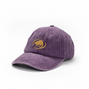 A purple washed cotton baseball cap with a gold embroidered logo on the front, displayed on a white surface against a neutral gray background.