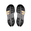 A pair of athletic shoes shown from the bottom, displaying their black and gray textured outsoles with gold-colored accents on a plain white background.