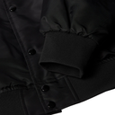 Close-up detail of a black jacket showing the sleeve cuff, ribbed trim, and snap-button front closure.