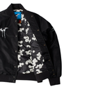 A black nylon bomber jacket with a white camouflage pattern lining, featuring a white graphic print on the left chest and a blue brand label at the collar.