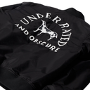 Close-up of the back of a black bomber jacket featuring a large white graphic print with the words 'UNDER RAISED AND OBSCURE' and a dog silhouette.