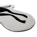 A close-up of a white textured rug with a black abstract curved pattern, shown on a plain white background.