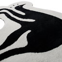 A close-up of a plush shag rug with a bold black and white abstract design, showing the soft texture of the fibers against a clean white background.