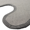 Close-up of a gray woven textile product, likely a cushion or pad, showing a curved seam with a contrasting black-and-white herringbone braided edge on a white background.