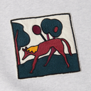 A close-up of a white heathered fabric garment featuring a square embroidered patch with a stylized red dog, dark blue trees, and a yellow accent.