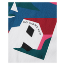A close-up of a graphic t-shirt featuring a stylized white house with the text 'GO HOME NOW' printed on it. The design uses a bold color palette of blue, red, pink, teal, and white, with a small black script logo in the bottom right corner.