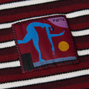 Close-up of a striped knit garment in burgundy, white, and black, featuring a square embroidered patch with a blue dancer silhouette, a yellow sun, and the word 'parra'.