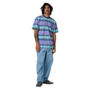 Person wearing a patterned shirt and light blue pants on a white background