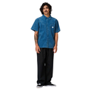 Man wearing a blue denim shirt and black pants on a white background