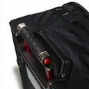 Close-up of a black rolling suitcase handle with a textured black grip, silver metal end caps, and a red button, mounted on a black suitcase against a white background.