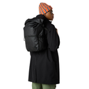 Person wearing a black coat and backpack with an orange and blue striped beanie on a white background