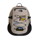 A beige and black The North Face backpack with decorative laces and several colorful embroidered patches on the front, shown against a plain white background.