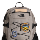 A light gray The North Face backpack with black zippers, compression straps, and two patches on the front pocket, shown against a plain white background.