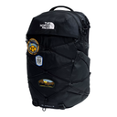 A black The North Face backpack with multiple patches and bungee cord details, shown on a plain white background.