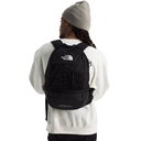 A person shown from the back wearing a black The North Face backpack, a white sweatshirt, and a gray beanie against a plain white background.