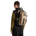 A man wearing a tan and black The North Face backpack, shown from the back and side against a plain white background.