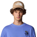 Person wearing a blue sweatshirt with The North Face logo, wearing a beige cap with the brand's logo.