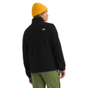 Person wearing a black fleece jacket with a brand logo on the back, yellow beanie, and green pants.