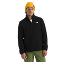 Person wearing a black fleece pullover with a logo, yellow beanie, and green pants on a white background