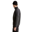 A man in profile wearing a black knit beanie and a black quarter-zip fleece jacket, photographed against a solid white background.