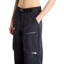 A close-up of a person wearing black The North Face pants with a black belt, standing against a white studio background.