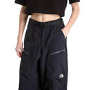A model wearing black wide-leg technical pants with zippered cargo pockets and a small white The North Face logo on the lower leg, paired with a black cropped top against a white background.