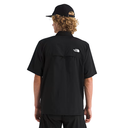 Person wearing a black shirt with a logo on the back, standing against a white background