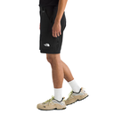 Person wearing black shorts with a brand logo, white socks, and beige sneakers on a white background