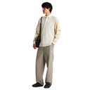 Person wearing a beige shirt and gray pants with a black bag on a white background