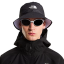 Person wearing a black bucket hat and sunglasses with The North Face logo on a white background