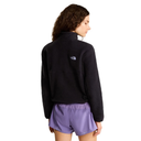 A woman shown from the back wearing a black fleece quarter-zip pullover with a small white embroidered The North Face logo on the upper back, paired with purple athletic shorts, against a light gray studio background.